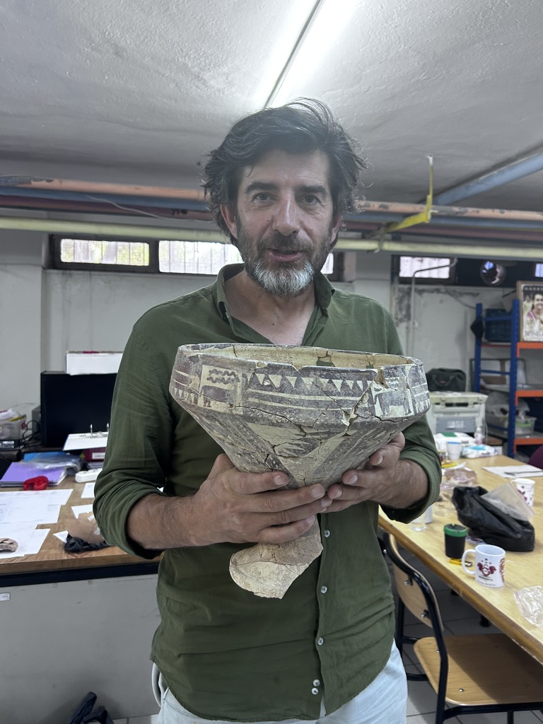 Mustafa Kibaroğlu holding a reconstructed painted ceramic vessel